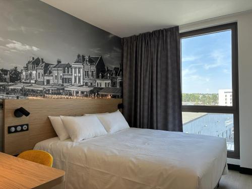 a hotel room with a bed and a large window at B&B HOTEL Amiens Sud in Amiens