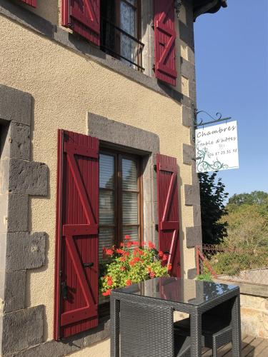 a window with red shutters and a table in front of a building at A l'Aube des Volcans in Charbonnières-les-Vieilles