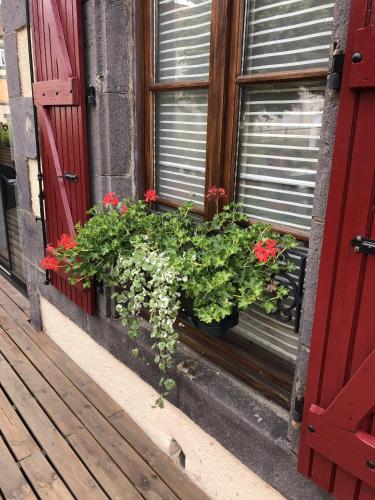 a window with a red door and flowers in a window box at A l'Aube des Volcans in Charbonnières-les-Vieilles