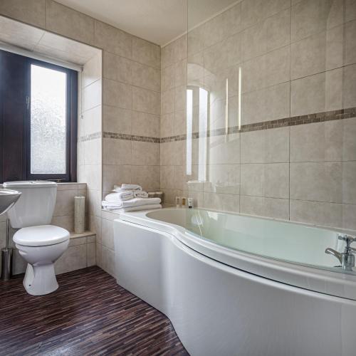 a bathroom with a tub and a toilet and a sink at The Old Bridge Inn, Holmfirth, West Yorkshire - The Coaching Inn Group in Holmfirth