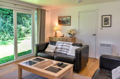 a living room with a leather couch and a table at Finest Retreats - Brockwood in Bradworthy