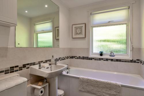 a bathroom with a sink and a tub and a mirror at Finest Retreats - Brockwood in Bradworthy