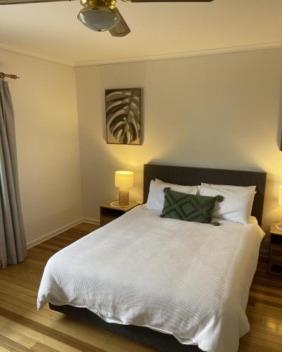 a bedroom with a bed with white sheets and green pillows at Barossa Suites on Basedow in Tanunda