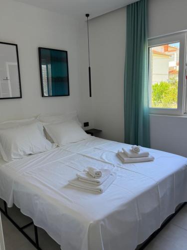 a white bed with two towels and a window at Moderni apartman Tina in Mundanije