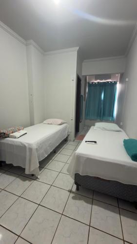 a bedroom with two beds and a tiled floor at BG Hospedagens in Paracatu