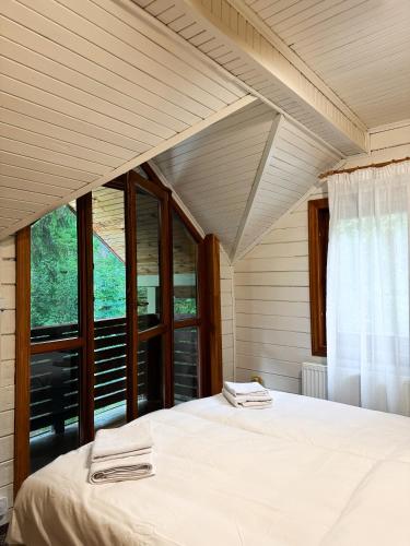 a bedroom with a bed and a large window at Котеджі Сім Вітрів in Volosyanka