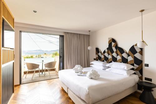 a bedroom with a large bed and a balcony at Hôtel & Spa Rocabella in LʼÎle-Rousse