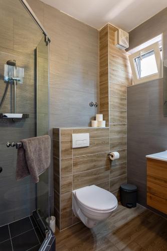 a bathroom with a toilet and a glass shower at Holiday Hotel Siófok in Siófok