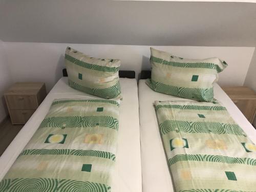 two beds in a small room with green and white pillows at Nice Big House in Balatonfenyves