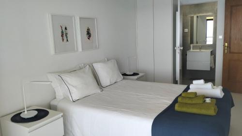 a bedroom with a white bed with towels on it at Edifício Panorâmico - Falésia de Sesimbra in Sesimbra