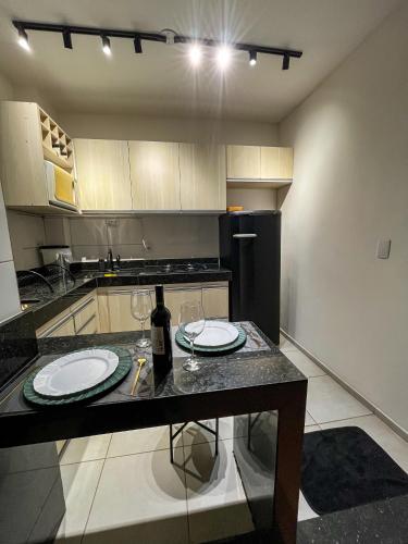 a kitchen with a table with two plates and wine glasses at Apt Moderno e Confortavel 7 min do Centro em 7L in Sete Lagoas