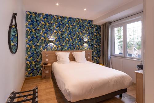 a bedroom with a bed with a blue and yellow wall at Hotel Aria in Nice