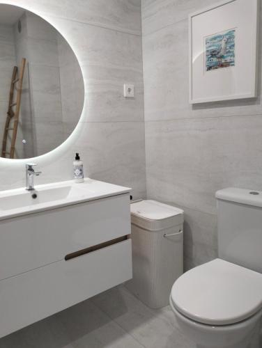 a bathroom with a toilet and a sink and a mirror at Edifício Panorâmico - Falésia de Sesimbra in Sesimbra