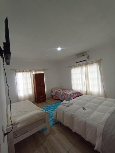 a bedroom with two beds and a tv and windows at Hotel Maipú in Maipú