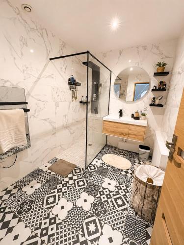 a bathroom with a shower and a black and white floor at Maison de charme avec Jacuzzi privé in Sarcelles