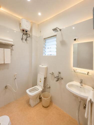 a white bathroom with a toilet and a sink at Hotel Pushparaj Puri - Beach front Hotel near Light House - Sea Facing AC Rooms - with Restaurant, Parking Facilities in Puri