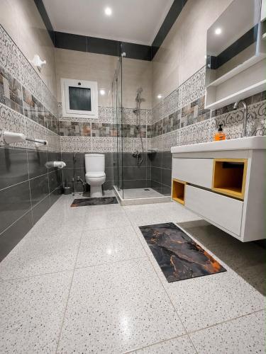 a bathroom with a toilet and a glass shower at Nubian Villa with Private Pool in Naj‘ al Aḩwāl