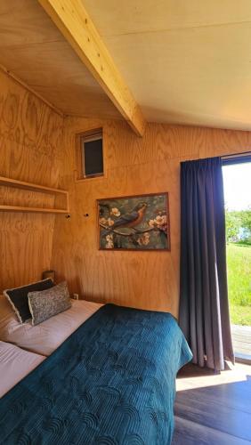 a bedroom with a bed and a window at Tiny house De Ljip in Westergeest