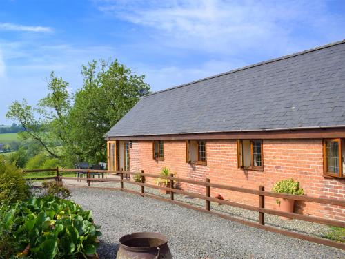 a brick house with a wooden fence around it at Talog Barn-Uk31366 in Tregynon