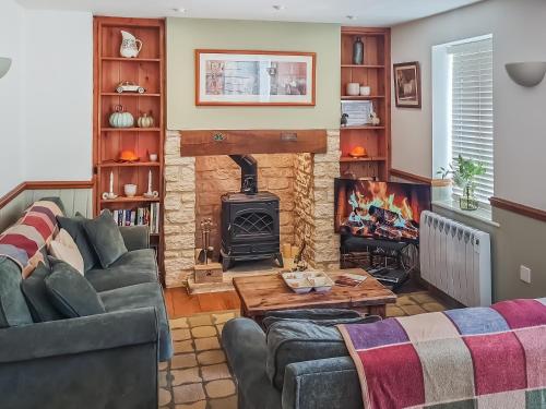 a living room with a couch and a fireplace at Moorhens Cottage in Somerford Keynes
