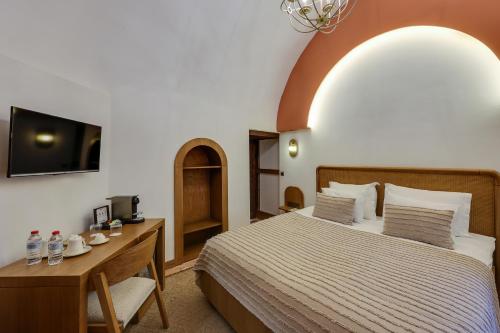 a bedroom with a bed and a desk and a tv at Silk Road Museum Hotel in Tokat