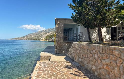 a building with a stone wall next to the water at Nice Home In Karlobag With Wifi in Karlobag