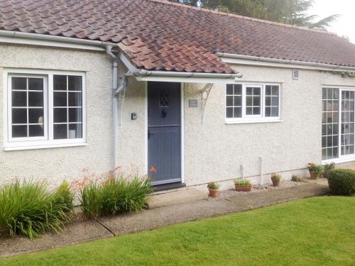 a white house with a blue door and a yard at Clinton Cottage in Yaxham