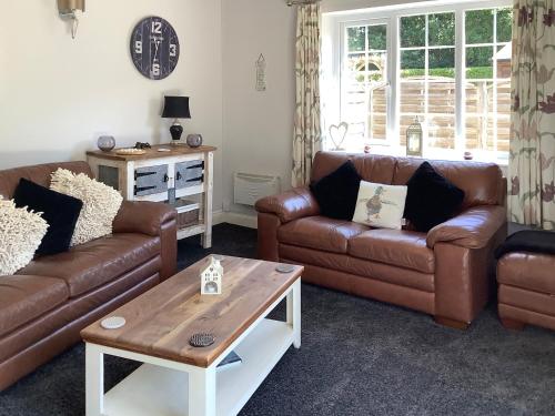 a living room with two couches and a coffee table at Clinton Cottage in Yaxham
