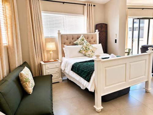 a bedroom with a white bed and a couch at Calypso Sunset Accommodation in Langebaan