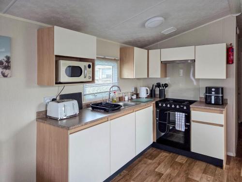 a kitchen with white cabinets and a sink and a microwave at Waterlily in Lancaster