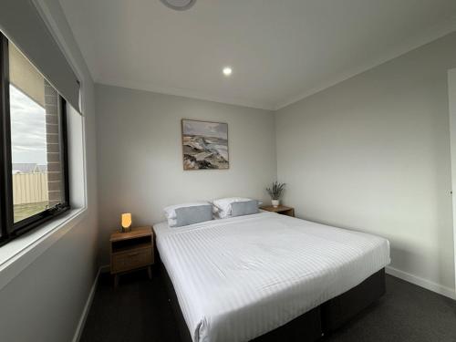 a white bedroom with a bed and a window at Wyoming Ave in North Wagga