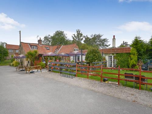 a fence with benches and tables in front of a house at The Stirrup Cottage in Blyborough