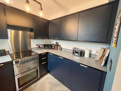 a kitchen with black cabinets and stainless steel appliances at Whitstable May House in Whitstable