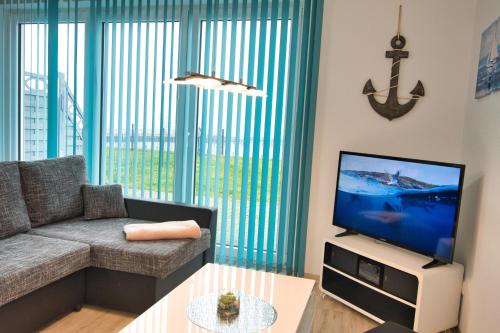 a living room with a couch and a tv at Ferienhaushälfte "Ausblick" in Sundhagen-Niederhof