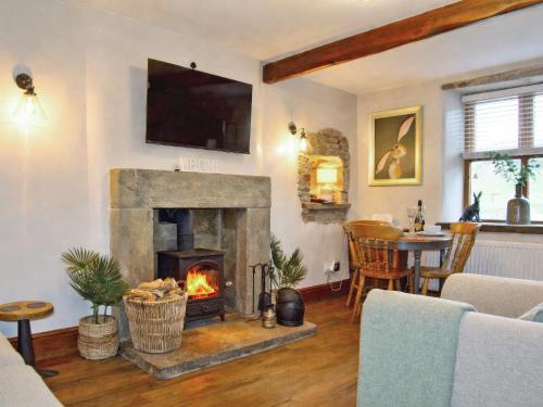 a living room with a fireplace and a tv at Quarry Cottage in Barnoldswick