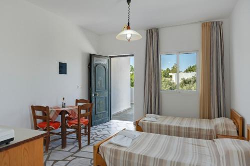 a hotel room with two beds and a table and a dining room at Ilios and Irene 5 in Mastihari