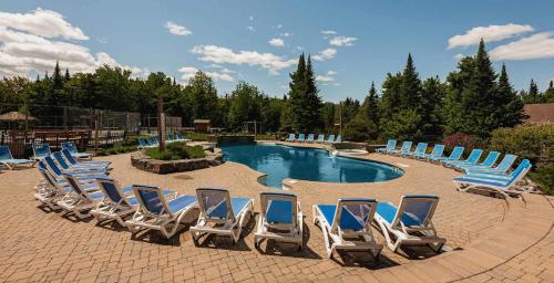 a group of chairs sitting around a swimming pool at Spa Pool & Sauna - Laurentides Serenity in Mille-Isles