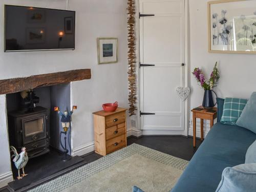 a living room with a blue couch and a fireplace at Tan Bryn - Uk44151 in Llanallgo