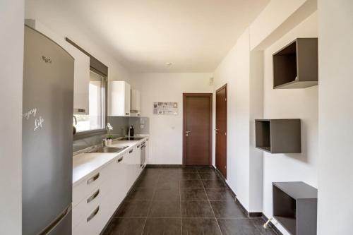 a kitchen with white cabinets and a tile floor at Sani Invictus Villa in Sani Beach
