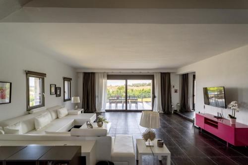 a living room with white furniture and a large window at Sani Invictus Villa in Sani Beach