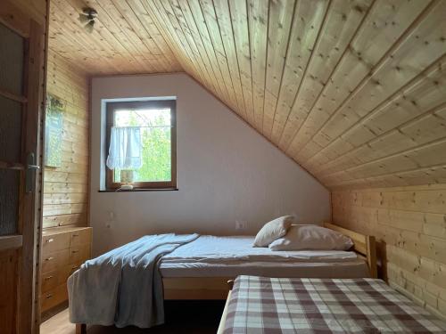 a bed in a room with a wooden ceiling at Domki Gościniec Bobolin in Bobolin
