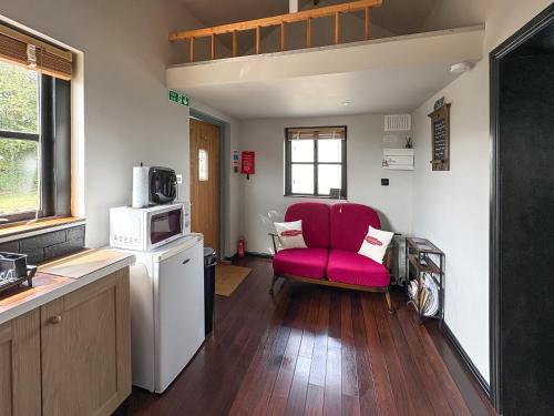 a living room with a red chair and a microwave at The Weighbridge in North Clifton