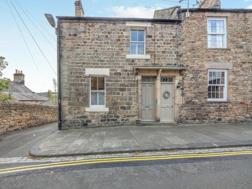 a brick building with a door on a street at Chareside Cottage in Corbridge