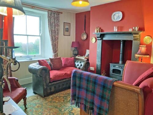 a red living room with a couch and a fireplace at Downhouse Cottage in Treknow