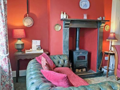 a living room with a couch and a wood stove at Downhouse Cottage in Treknow
