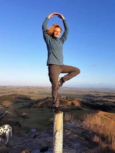 a woman is standing on a pole on a hill at Tokatoka views Farmstay in Ruawai