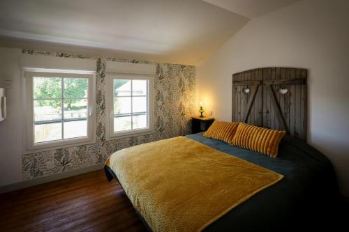 a bedroom with a bed and two windows at Gîte les clés de l'émeraude in Bergnicourt
