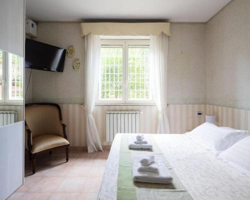 a bedroom with a bed and a chair and a window at Villa Ennio in Ciampino