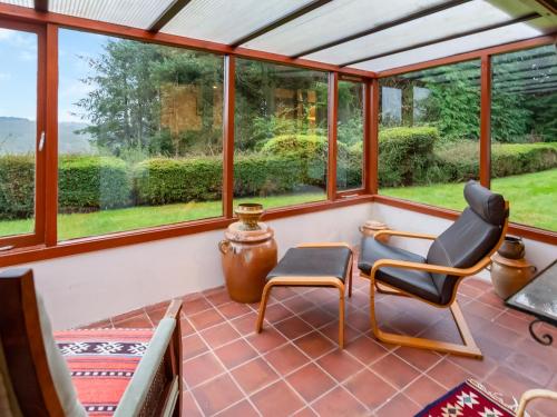 a screened in porch with two chairs and windows at Smiddy Cottage in Alyth