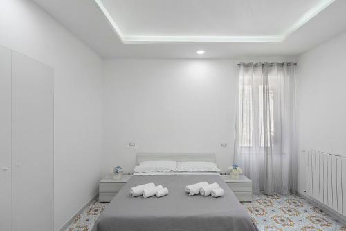 a white bedroom with a bed with three pillows at La Casa Di Zio Michelino in Pimonte